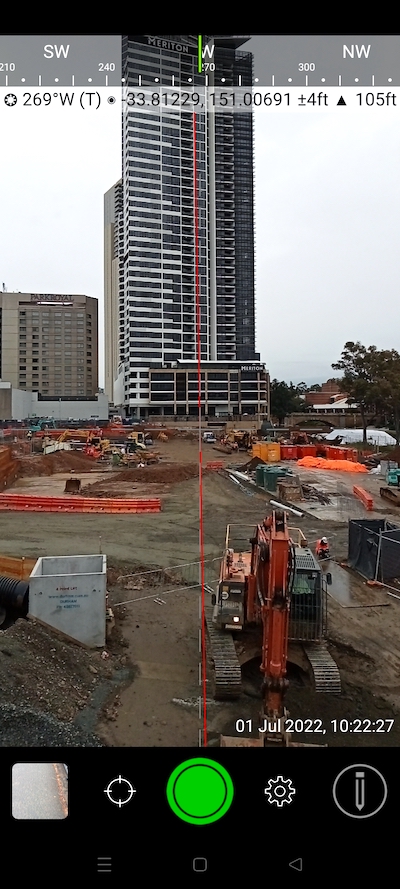 Excavator on construction site with date, time and location overlays.